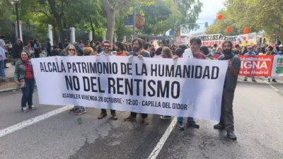 Grupo de personas de Alcalá de Henares en la manifestación de la vivienda. Sujetando una pancarta dónde se lee: "Alcalá patrimonio de la humanidad, no del rentismo. Asamblea de vivienda 26 de octubre, 12:00, en la capilla del oidor"